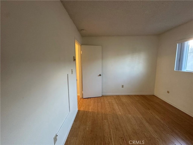 spare room featuring baseboards and wood finished floors