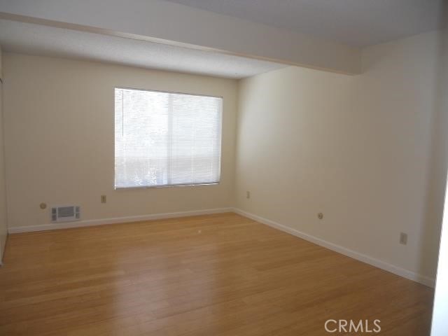 spare room with light wood-style floors, visible vents, and baseboards