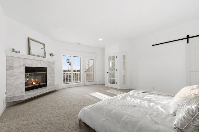 bedroom with carpet floors, a fireplace, a barn door, access to outside, and recessed lighting