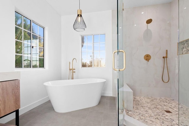 full bath featuring baseboards, a freestanding tub, tile patterned floors, and a shower stall