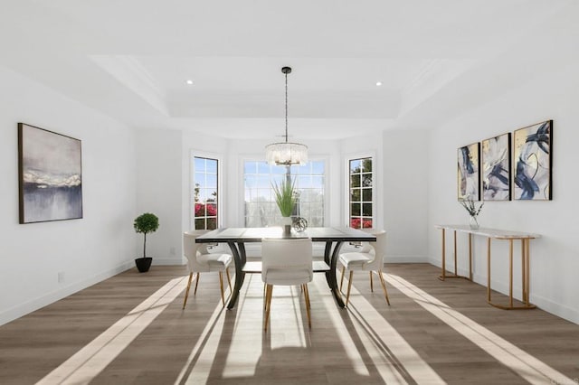 dining area featuring baseboards, a tray ceiling, wood finished floors, and a notable chandelier