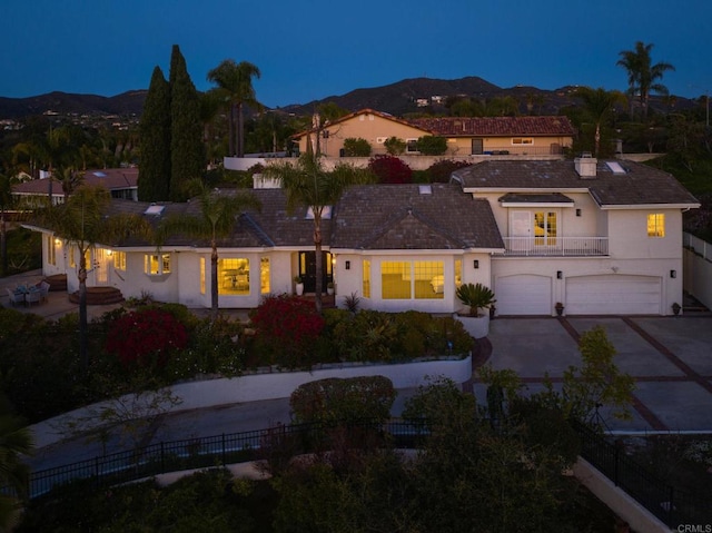 view of front of property featuring concrete driveway, stucco siding, an attached garage, a balcony, and a mountain view