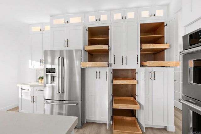 kitchen with light countertops, appliances with stainless steel finishes, white cabinetry, open shelves, and light wood-type flooring