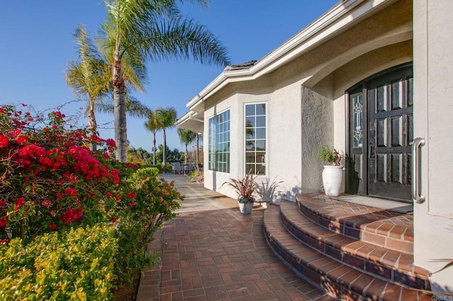 property entrance with stucco siding and a patio area