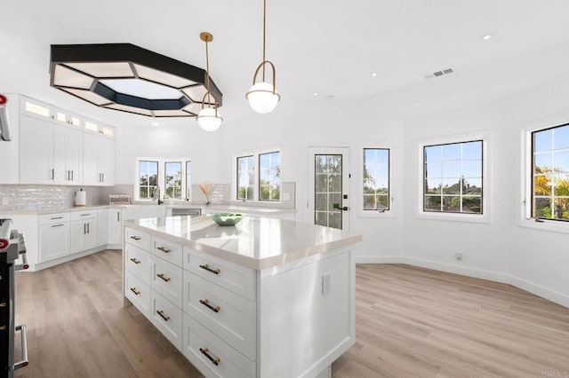 kitchen with light wood-style flooring, visible vents, a healthy amount of sunlight, and backsplash
