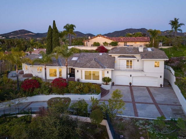 mediterranean / spanish house featuring stucco siding, fence, a balcony, a mountain view, and a garage