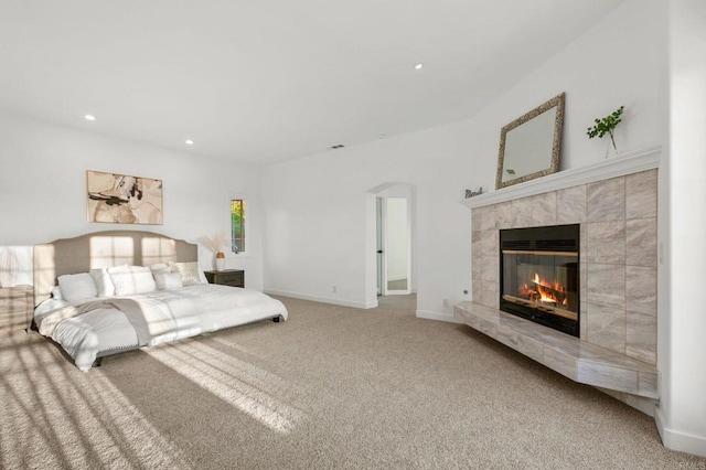 carpeted bedroom featuring arched walkways, baseboards, a fireplace, and recessed lighting