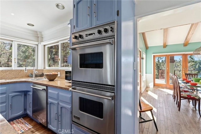 28019 N Shore Rd, Lake Arrowhead, CA 92352 - kitchen featuring appliances with stainless steel finishes, hardwood / wood-style flooring, blue cabinets, ornamental molding, and stone counters