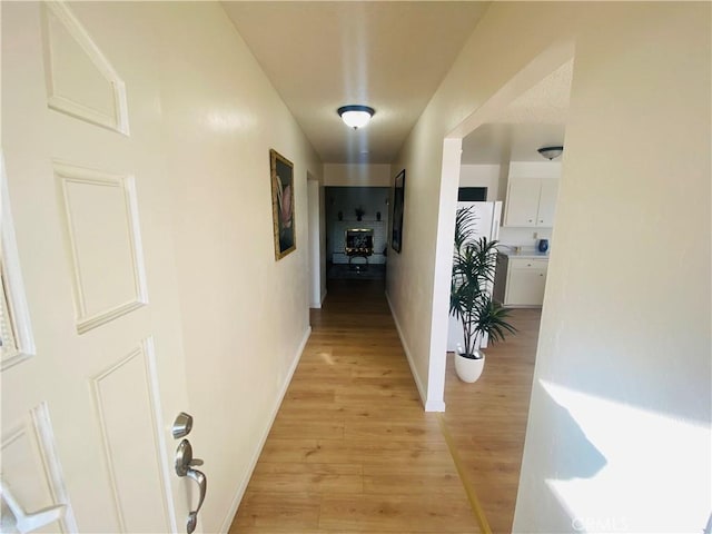 hall featuring light wood-style floors and baseboards