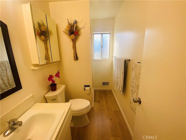 bathroom featuring visible vents, baseboards, toilet, and wood finished floors