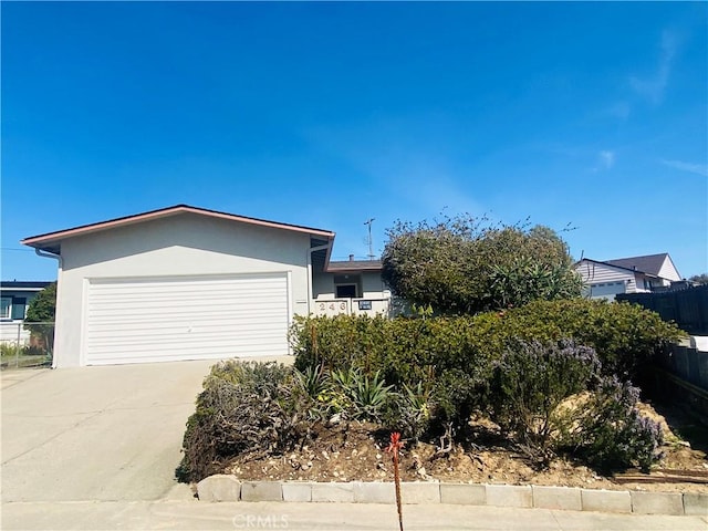 view of front facade featuring stucco siding, driveway, an attached garage, and fence