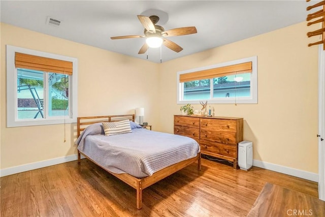 bedroom with visible vents, multiple windows, baseboards, and wood finished floors