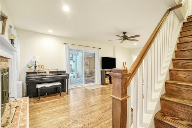interior space featuring a ceiling fan, recessed lighting, stairway, light wood-style floors, and a fireplace