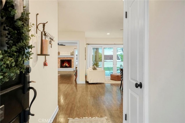 foyer entrance featuring baseboards, wood finished floors, and a fireplace
