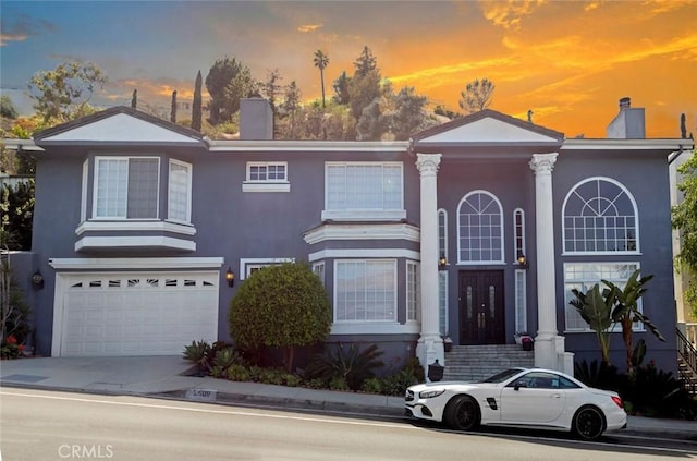 view of front of property featuring stucco siding, a garage, and a chimney