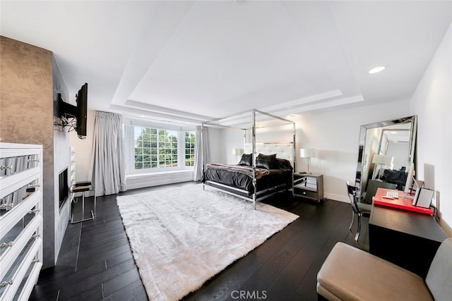bedroom featuring recessed lighting, dark wood-style flooring, baseboards, and a raised ceiling
