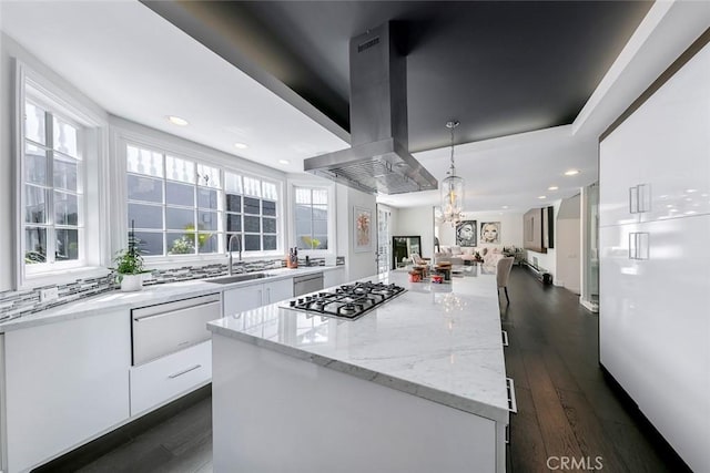 kitchen featuring white cabinets, a sink, open floor plan, a warming drawer, and island range hood