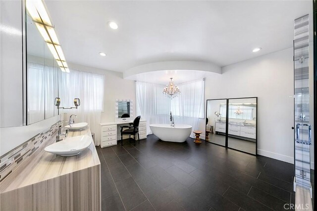 full bathroom featuring vanity, a freestanding tub, an inviting chandelier, and plenty of natural light
