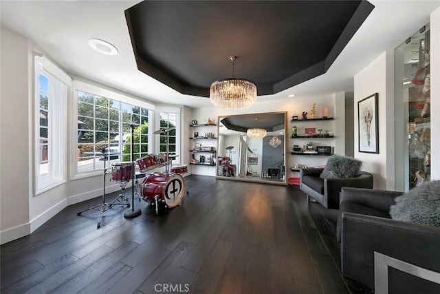 recreation room featuring a tray ceiling, a notable chandelier, dark wood finished floors, and baseboards