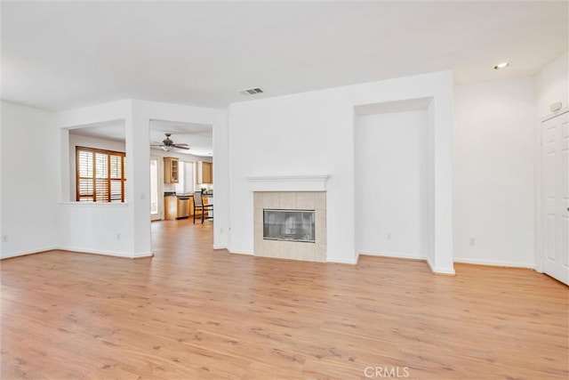 unfurnished living room with visible vents, a fireplace, light wood finished floors, baseboards, and ceiling fan