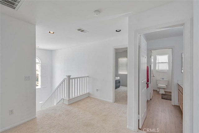 corridor featuring an upstairs landing, visible vents, recessed lighting, and light carpet