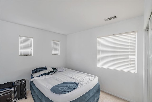bedroom with baseboards, visible vents, and light carpet
