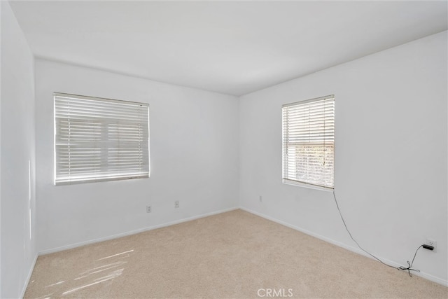 carpeted empty room featuring baseboards