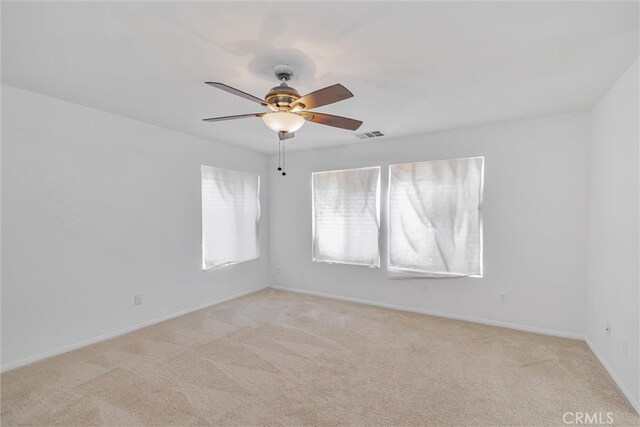 unfurnished room with visible vents, a ceiling fan, light colored carpet, and baseboards