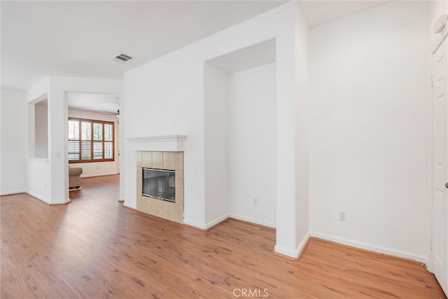 unfurnished living room featuring wood finished floors, baseboards, visible vents, a fireplace, and ceiling fan