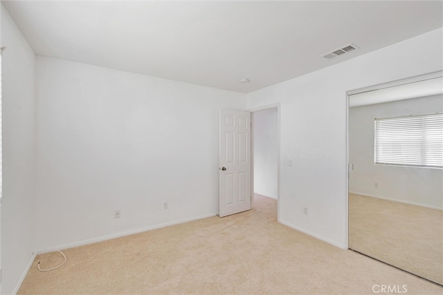 spare room with visible vents, baseboards, and light colored carpet