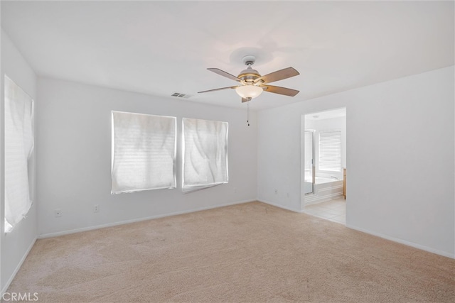 empty room featuring visible vents, light colored carpet, baseboards, and ceiling fan