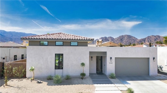 view of front of home with stucco siding, driveway, a garage, and a mountain view