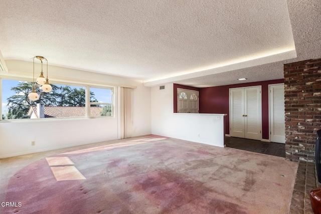 spare room with visible vents, a textured ceiling, a wood stove, and carpet floors