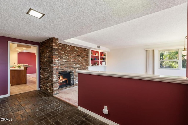 interior space featuring a brick fireplace, baseboards, brick floor, and a textured ceiling