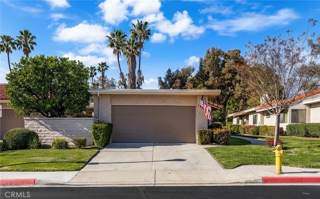 view of front of home with stucco siding, driveway, a front yard, and a garage