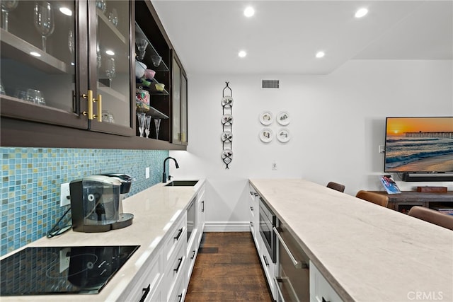 6 Via Presea, Coto De Caza, CA 92679 - kitchen with black electric stovetop, a sink, dark wood-style floors, glass insert cabinets, and decorative backsplash