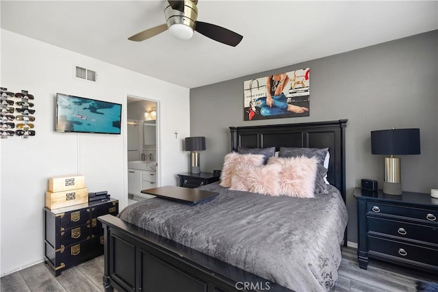 bedroom with wood finished floors, visible vents, connected bathroom, and a ceiling fan