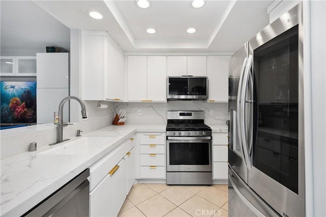 kitchen with stainless steel appliances, a sink, recessed lighting, white cabinetry, and a raised ceiling