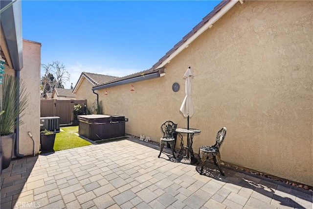 view of patio with fence, a hot tub, and central AC