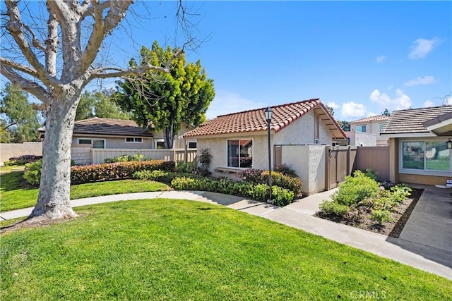mediterranean / spanish home featuring stucco siding, a tile roof, fence, and a front yard