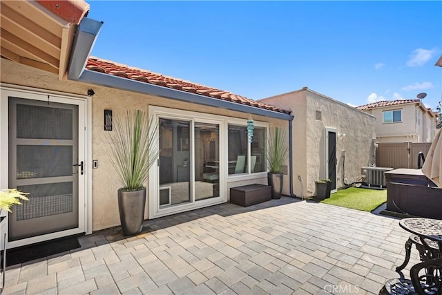 rear view of property featuring a tile roof, central AC unit, fence, a patio area, and stucco siding