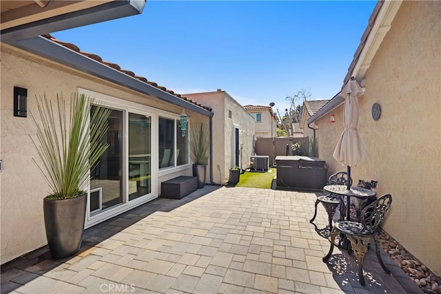 view of patio featuring central air condition unit, fence, and a hot tub