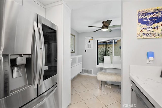 kitchen with light tile patterned floors, stainless steel fridge, ceiling fan, white cabinetry, and visible vents