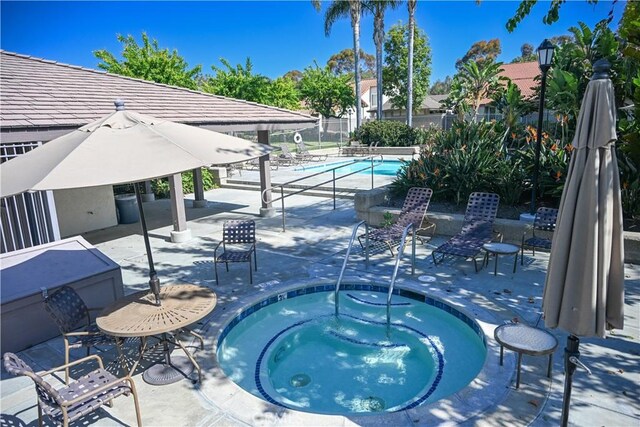 pool featuring a community hot tub, a patio area, and fence