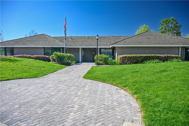 single story home with stucco siding and a front yard