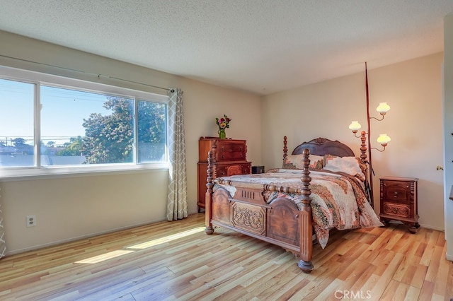 bedroom with light wood-style floors and a textured ceiling