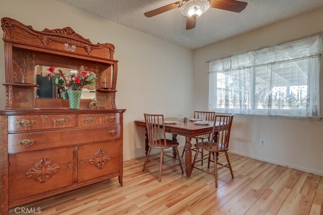 dining area featuring light wood-style flooring, a textured ceiling, baseboards, and ceiling fan