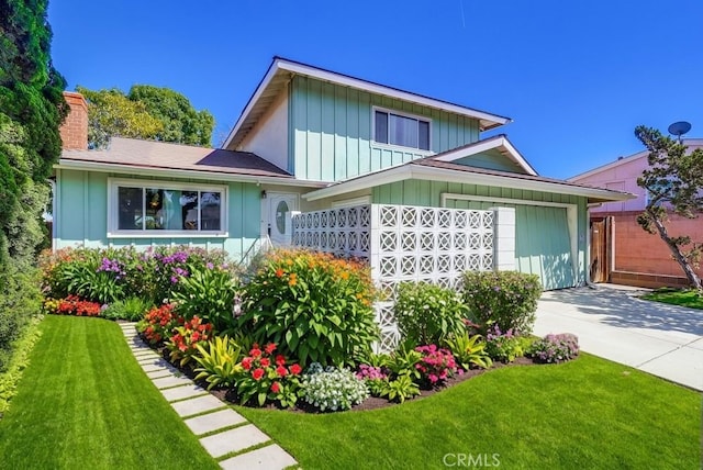 view of front of property with an attached garage, board and batten siding, concrete driveway, and a front yard