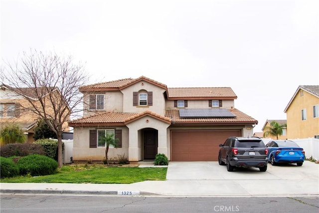 mediterranean / spanish house featuring an attached garage, roof mounted solar panels, stucco siding, fence, and concrete driveway