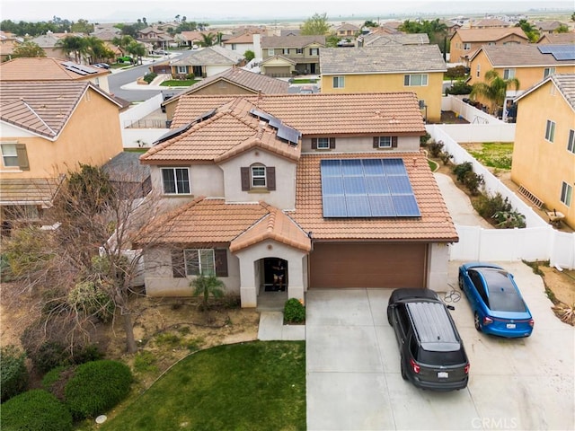 mediterranean / spanish-style house with stucco siding, concrete driveway, a tiled roof, and solar panels